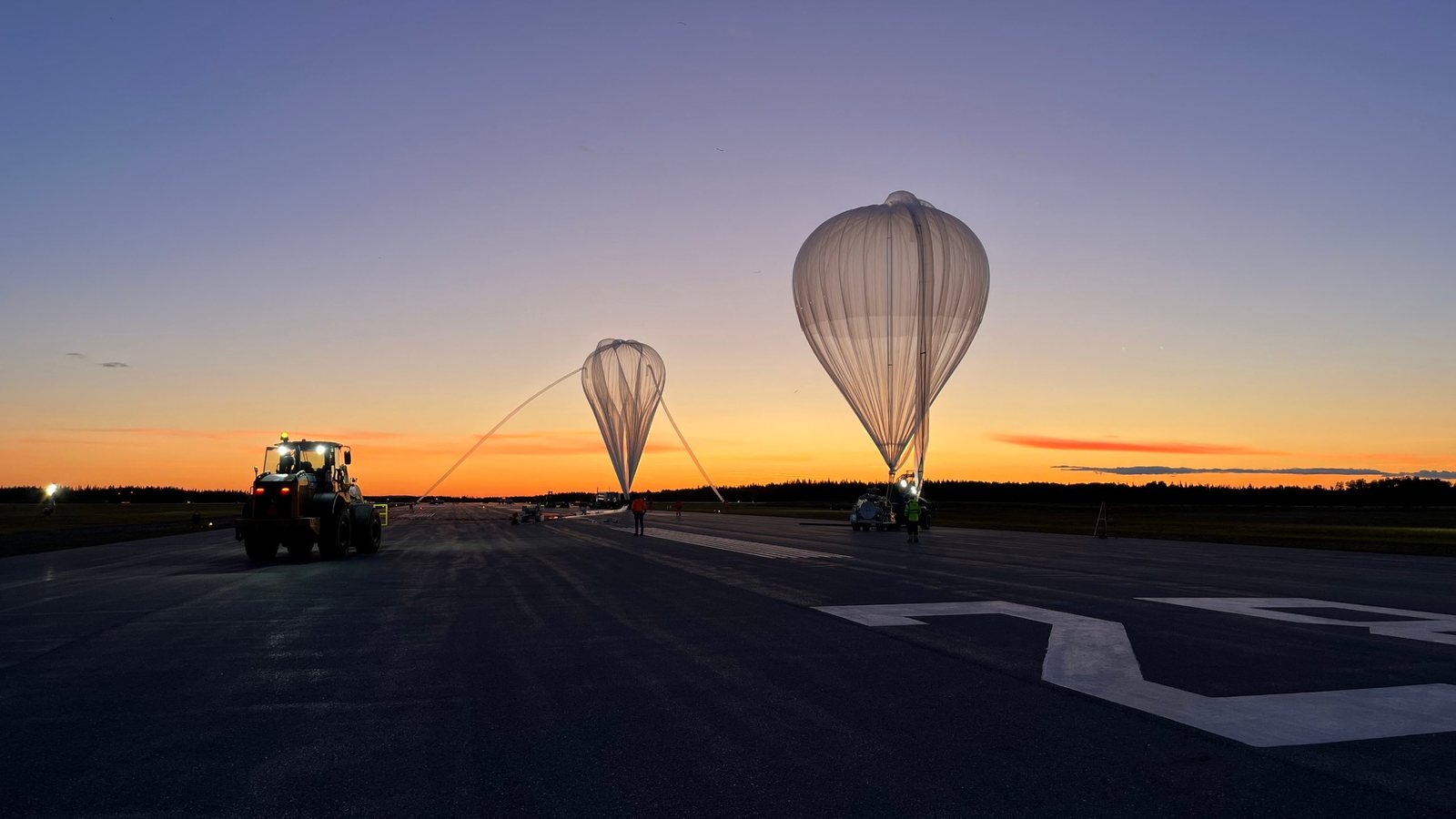 Stratospheric balloons being inflated on the runway at sunset